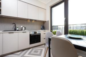 uma cozinha com armários brancos e uma mesa com cadeiras em City of the Kings - Indigo Apartment na Cracóvia