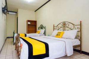 2 łóżka w pokoju z żółto-białą pościelą w obiekcie Astria Graha w mieście Bandung