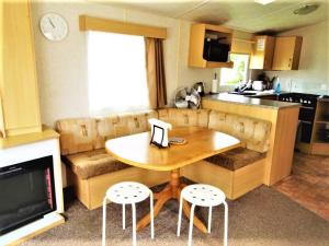 a kitchen with a table and two stools and a table at Devon Barnstaple Self Catering Accommodation Tarka Holiday Park, A14 Free Wi-Fi Spacious Tarka Holiday Park sleeps 5 Pets allowed Static Caravan home Devon EX31 4AU just 6 miles from Saunton Sands in Barnstaple