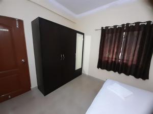 a bedroom with a black cabinet and a window at Raaj Inn studio's in Candolim