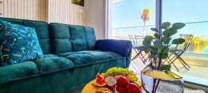ein Wohnzimmer mit einem blauen Sofa und einem Tisch mit Obst in der Unterkunft Phaedrus Living: Seaview Emerald Flat Lighthouse 48 in Paphos City