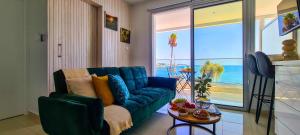 eine blaue Couch in einem Wohnzimmer mit Blick auf das Meer in der Unterkunft Phaedrus Living: Seaview Emerald Flat Lighthouse 48 in Paphos City