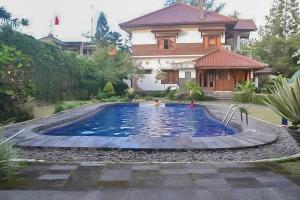 une maison avec une piscine en face d'une maison dans l'établissement RedDoorz Premium @ Griya Inkoppabri Cisarua Puncak, à Bogor