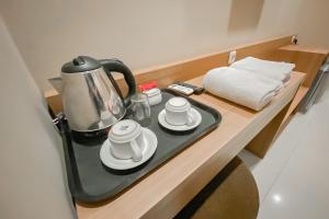 RedDoorz Premium @ Griya Inkoppabri Cisarua Puncak في بوغور: غلاية الشاي والأكواب على طاولة في الغرفة