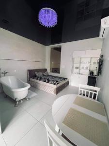 a bathroom with a tub and a bed and a table at Romeo VIP apartamentai in Panevėžys
