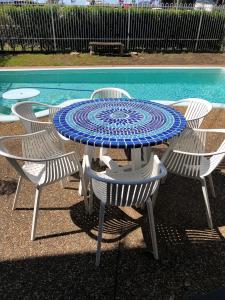 Avaleen Lodge Motor Inn في ناورا: طاولة وكراسي زرقاء وبيضاء بجانب مسبح
