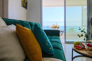 eine grüne Couch mit Kissen darauf in einem Wohnzimmer in der Unterkunft Phaedrus Living: Seaview Emerald Flat Lighthouse 48 in Paphos City