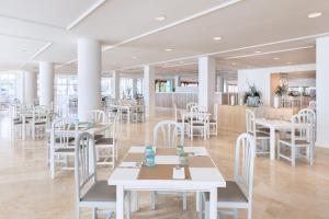 プエルト・デ・ナオスにあるSol La Palma Apartamentosの白いテーブルと白い椅子が備わるレストラン