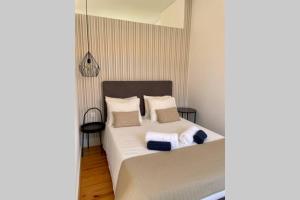 een slaapkamer met een bed met witte lakens en kussens bij Santo António Cozy Apartment in Porto