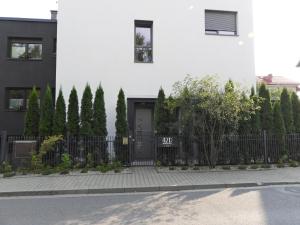 una casa blanca con una puerta negra y árboles en Apartament A2D Kraków en Cracovia