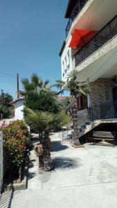 a building with palm trees and a red umbrella at Residenza Monopati Beach Methoni Pierias in Methoni