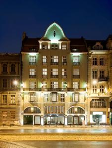 a large building with a green roof at night at Hotel NH Poznan in Poznań