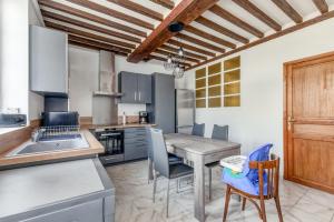 a kitchen with a table and chairs in a kitchen at Hamo - Maison à 600 m de la plage in Graye-sur-Mer +4 photos