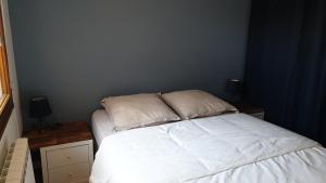 a bedroom with a bed with white sheets and pillows at COSY T3 LACANAU in Lacanau