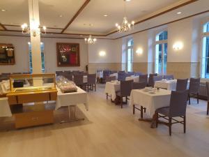 a restaurant with white tables and chairs and windows at Hasli Lodge in Meiringen