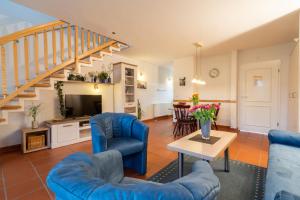 a living room with blue furniture and a staircase at Feriendorf Rugana - Klassik Appartement mit 2 Schlafzimmern und Terrasse C27 in Dranske