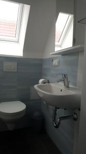 a bathroom with a sink and a toilet with two windows at Ferienwohnung auf dem Bauernhof in Großräschen
