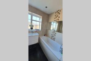 a bathroom with a tub and a sink at Luxurious 4 bed house with private garden in Saint Mary Cray