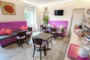 a restaurant with tables and chairs and purple booths at Hotel De La TA in Rennes