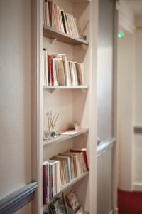 een boekenplank gevuld met boeken in een kamer bij Hotel De La TA in Rennes