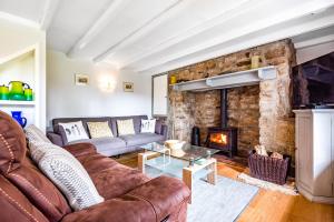 a living room with a couch and a fireplace at Tresowes Green Cottage in Helston