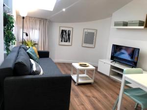 a living room with a black couch and a flat screen tv at INSIDEHOME Apartments - La Casita de Úrsula in Palencia