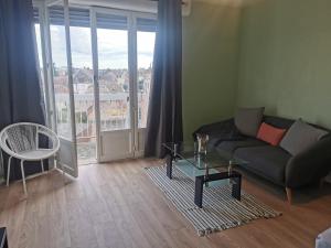 een woonkamer met een bank, een tafel en een raam bij Appartement, charmant type F1 37m2 vue dégagée, in Commentry