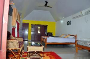 1 dormitorio con cama, sofá y sillas en Keratheeram Beach Resort, en Varkala