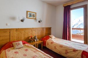 two beds in a room with a window at travelski home select - Résidence L'Ecrin des Sybelles in La Toussuire +13 photos