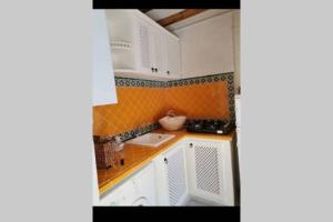 una pequeña cocina con armarios blancos y azulejos de color naranja en Dar El Halfaouine, en Túnez