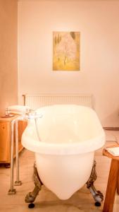 a white bath tub in a bathroom with a painting at Elma Guesthouse in Alba Iulia