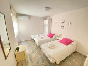 ベニドルムにあるSee The Sea - Mirando al Mar & APLUS Apartamentosのピンクの枕が付いたベッド2台が備わる客室です。