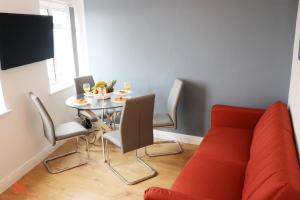 a dining room with a table and a red couch at Modern Newgate Apartments - Kingsbury Underground, All Local Amenities on Your Doorstep in Wealdstone