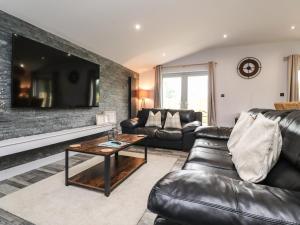 a living room with black leather furniture and a flat screen tv at Box Tree Escapes in Lancaster