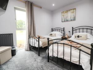 two beds in a bedroom with a window at Box Tree Escapes in Lancaster