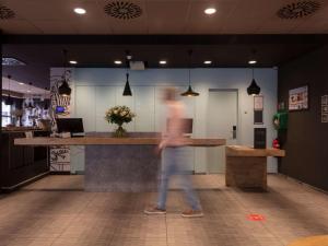 a person walking past a bar in a restaurant at ibis De Panne in De Panne