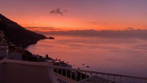 una puesta de sol sobre un cuerpo de agua con una ciudad en Hotel Holiday, en Praiano