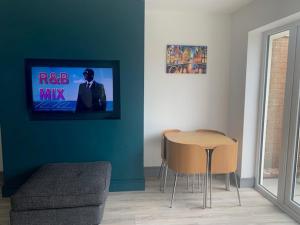 a living room with a table and a tv on the wall at Lovely 3-Bed House in Lytham Saint Annes in Saint Annes on the Sea