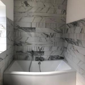 y baño con bañera blanca y paredes de mármol. en Lovely 3-Bed House in Lytham Saint Annes en Saint Annes on the Sea
