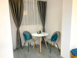 a table with two chairs and a white table with blue pillows at Signature Residence in Mediaş