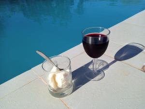 two glasses of wine and ice cream next to a pool at Fred Hunter Villa in Tiwi