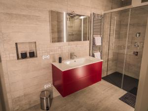 La salle de bains est pourvue d'un lavabo rouge et d'une douche. dans l'établissement Sweet Piccolo Loft in centro con incantevole idromassaggio, à Merano