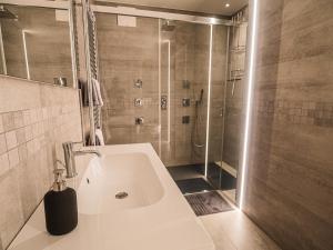 ein Bad mit einer Dusche und einem weißen Waschbecken in der Unterkunft Sweet Piccolo Loft in centro con incantevole idromassaggio in Meran