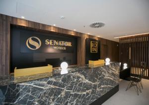 a hotel lobby with a counter with a sign on the wall at Senator Gandia in Gandía