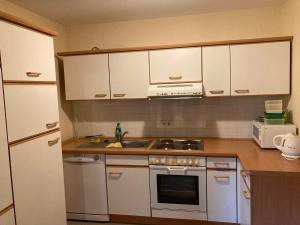 a kitchen with white cabinets and a stove top oven at Pension Tom´s Hütte in Nossen