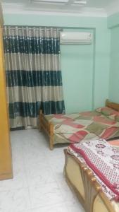 1 dormitorio con 2 camas y cortina en Taharka Nubian House, en Asuán