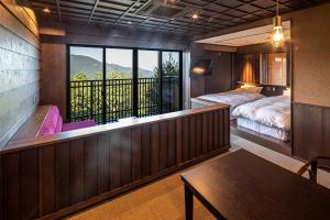 a hotel room with a balcony with a bed and a table at Hakone Kyuan in Hakone