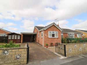 a brick house with a fence in front of it at The Corner Bungalow in Great Driffield