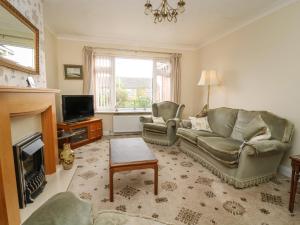 a living room with a couch and chairs and a television at The Corner Bungalow in Great Driffield