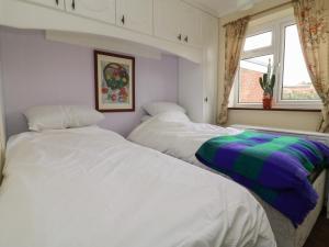 deux lits jumeaux dans une chambre avec fenêtre dans l'établissement The Corner Bungalow, à Great Driffield